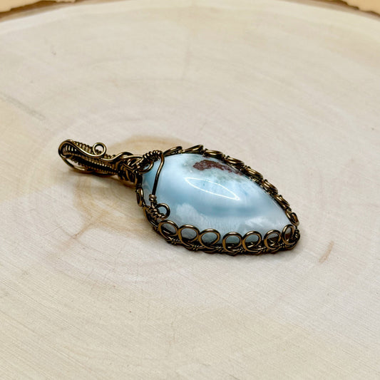 Pendant with a blue stone and bronze frame on a light wooden background