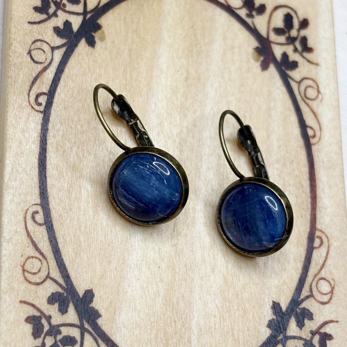 Pair of blue earrings with bronze settings on a decorative card.