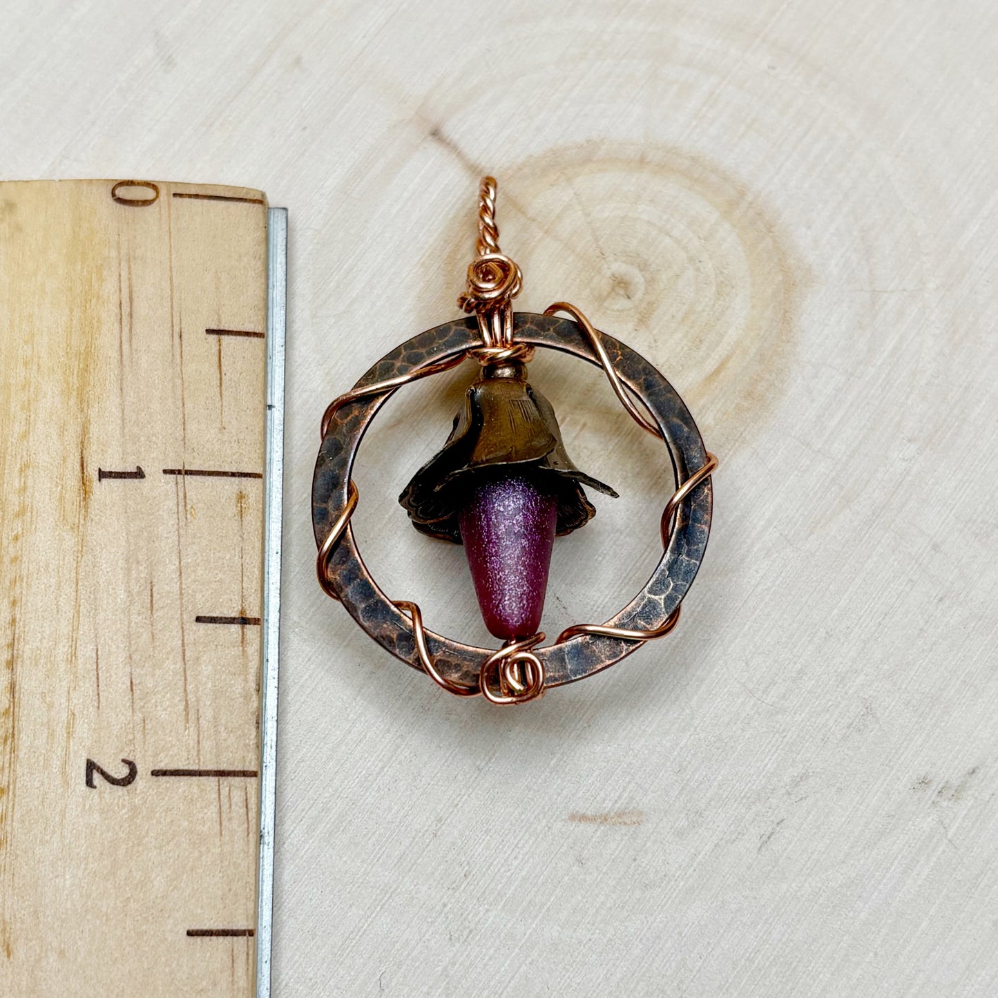 Copper and glass pendant on a wooden ruler for scale
