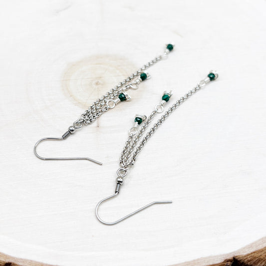 Silver earrings with green beads on a white background