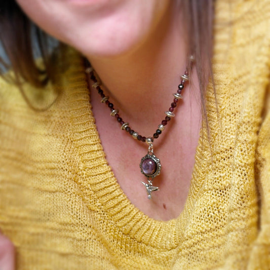 Close-up of a necklace with a pendant on a person wearing a yellow sweater.