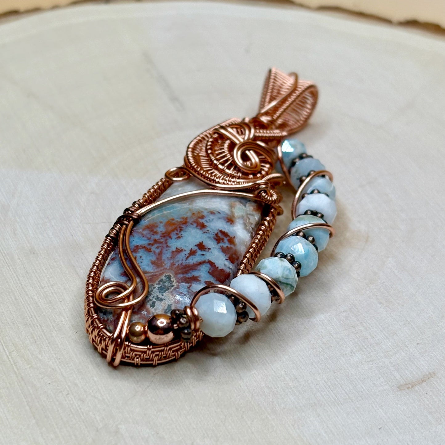 Copper pendant with Larimar stone and Larimar beads on a light background