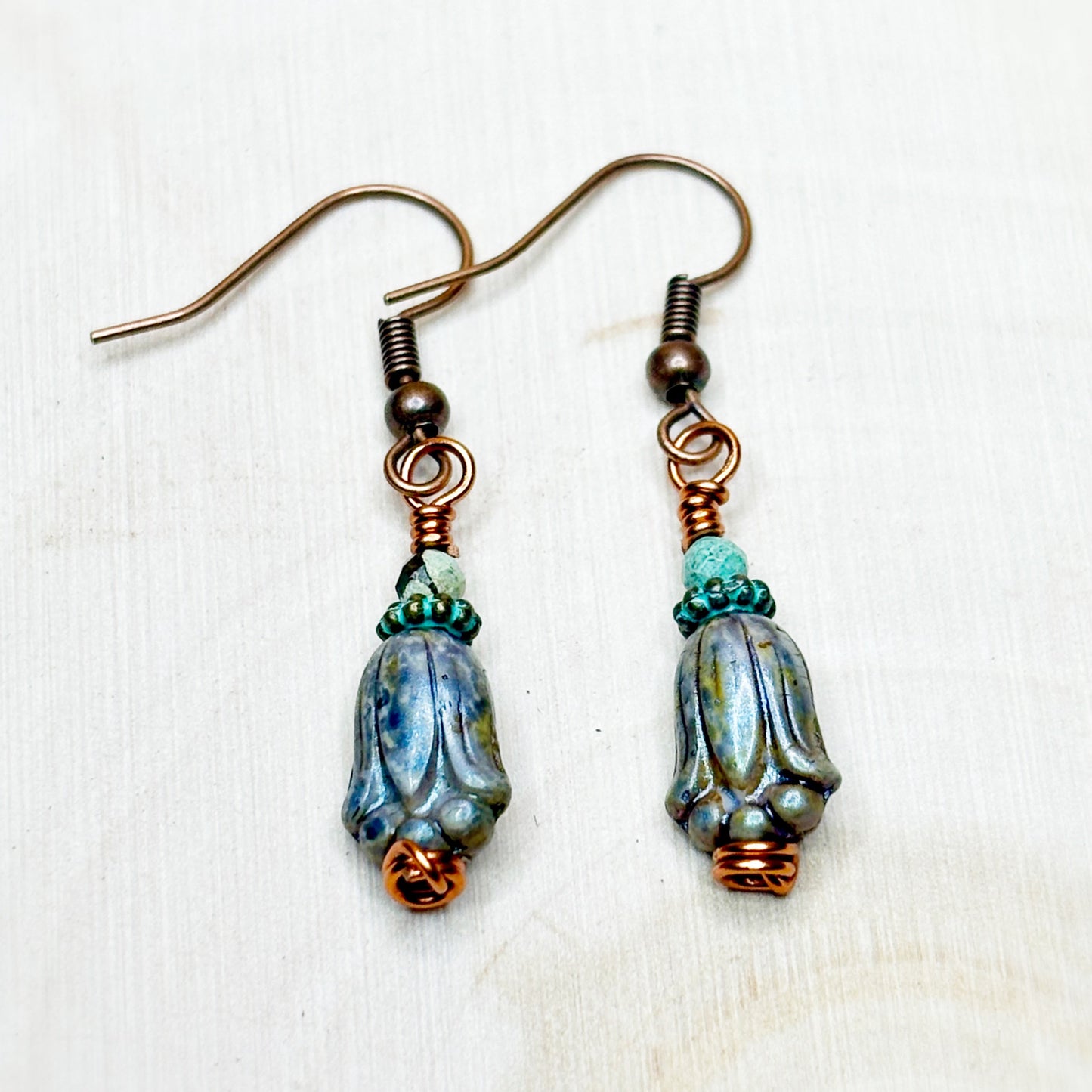 Pair of earrings with blue and copper beads on a white background