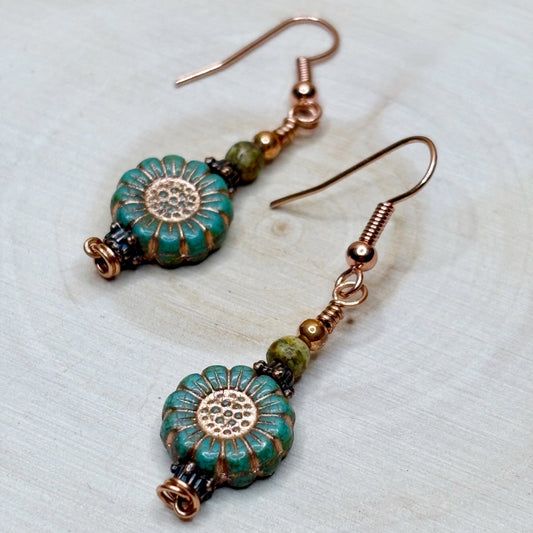 Copper earrings with blue and green laying on a wooden surface