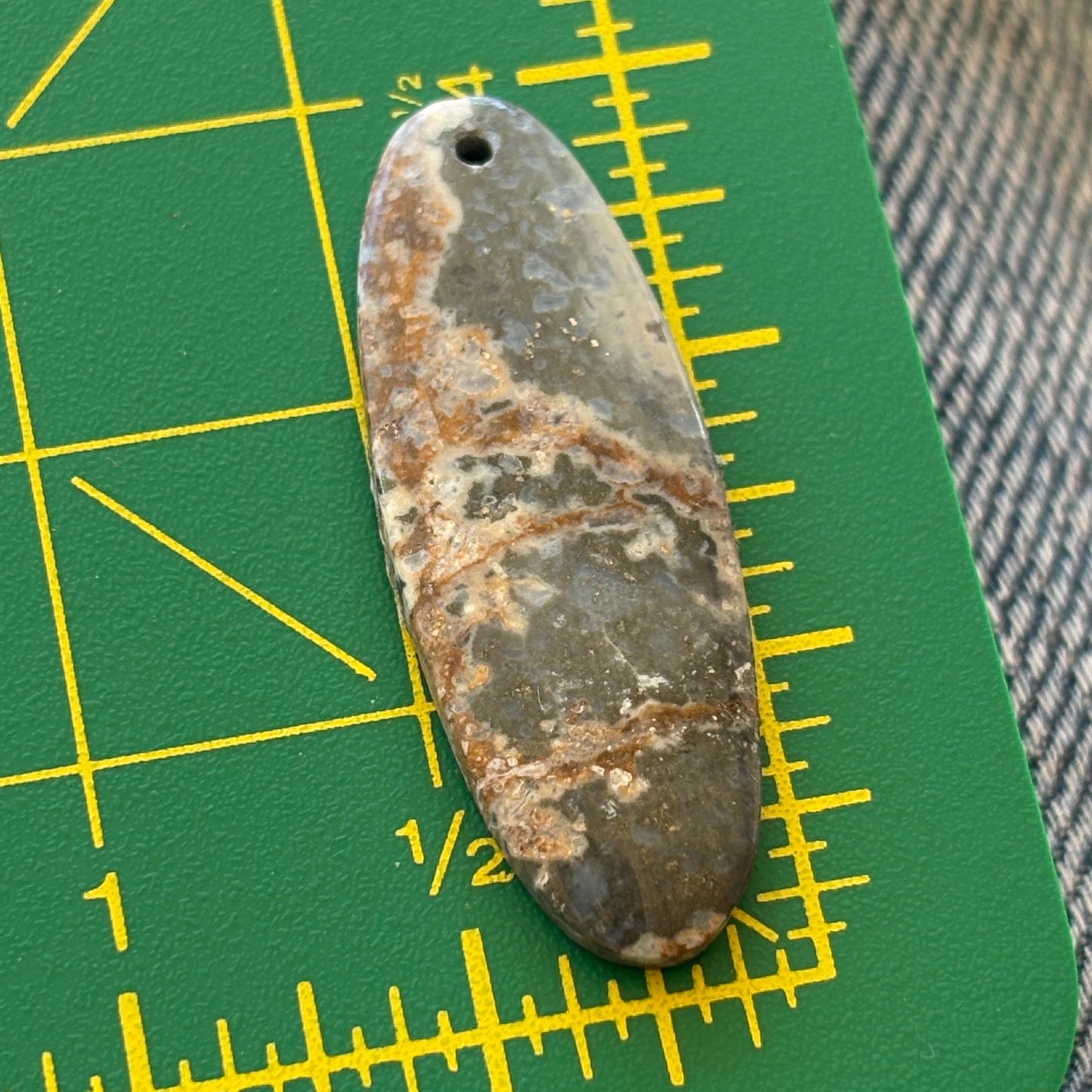 Rust-colored stone on a green cutting mat with yellow measurements