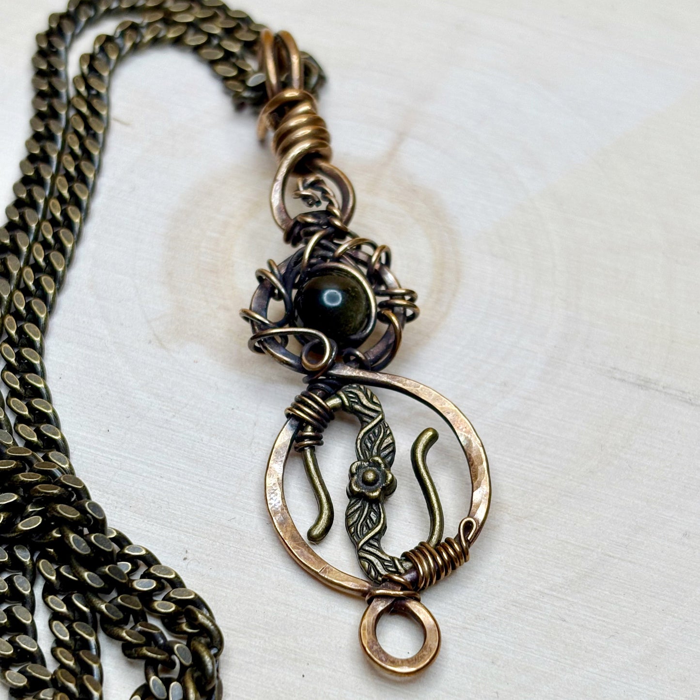 Bronze necklace with intricate pendant on a white background