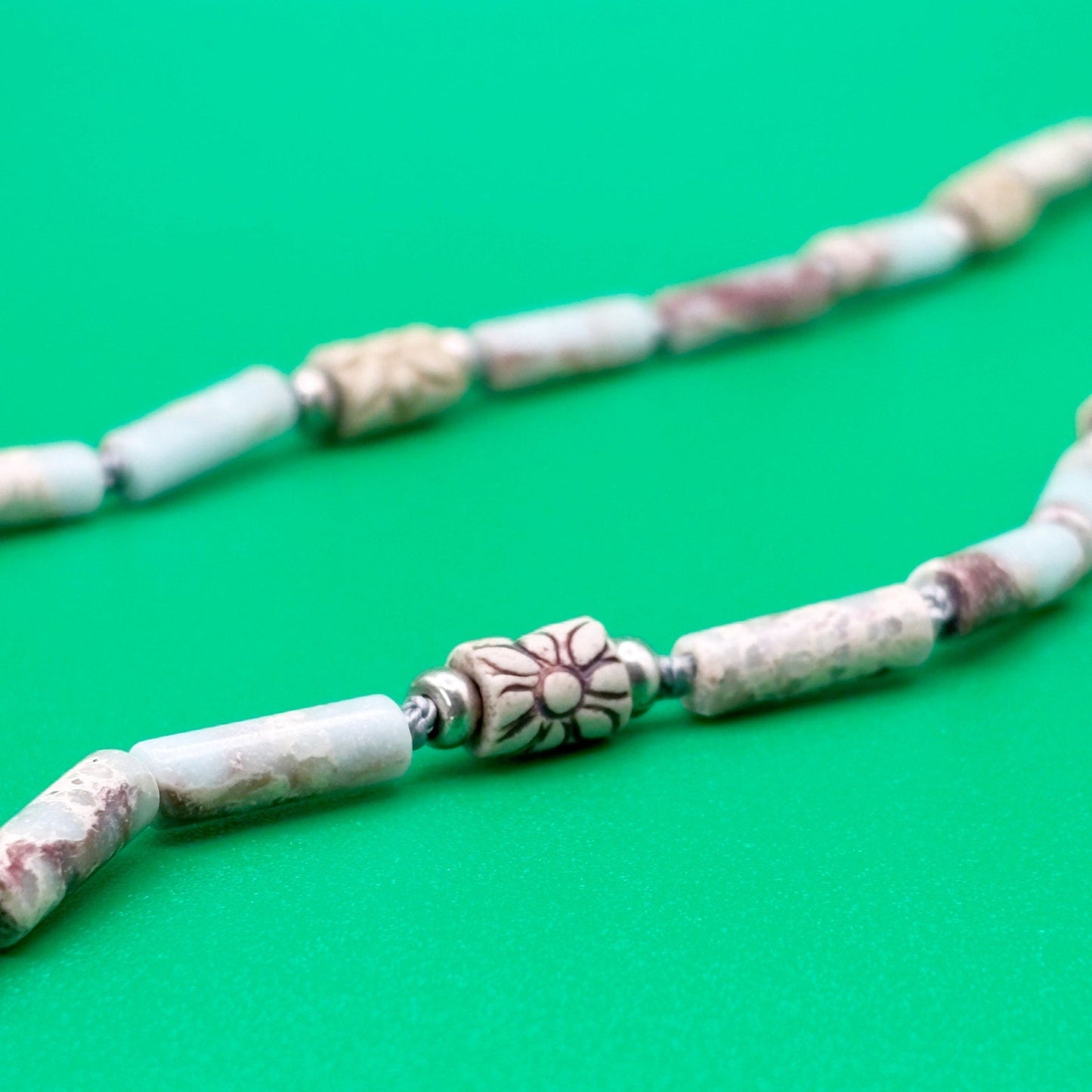 Necklace with marbled beads on a green background