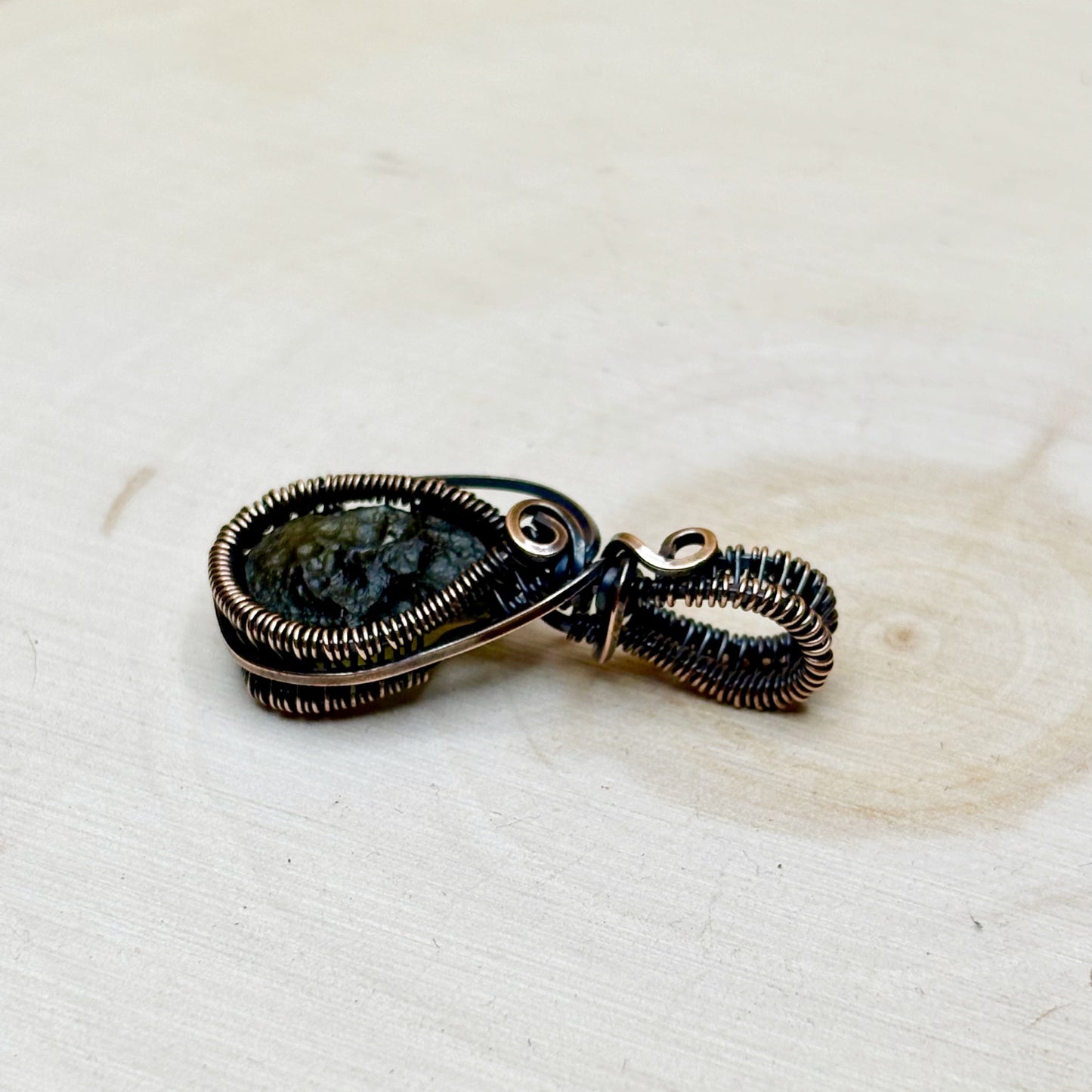Jewelry pendant with a Moldavite tektite on a textured white surface
