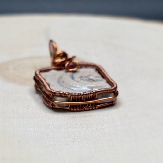 Copper-framed pendant with a textured surface on a neutral background