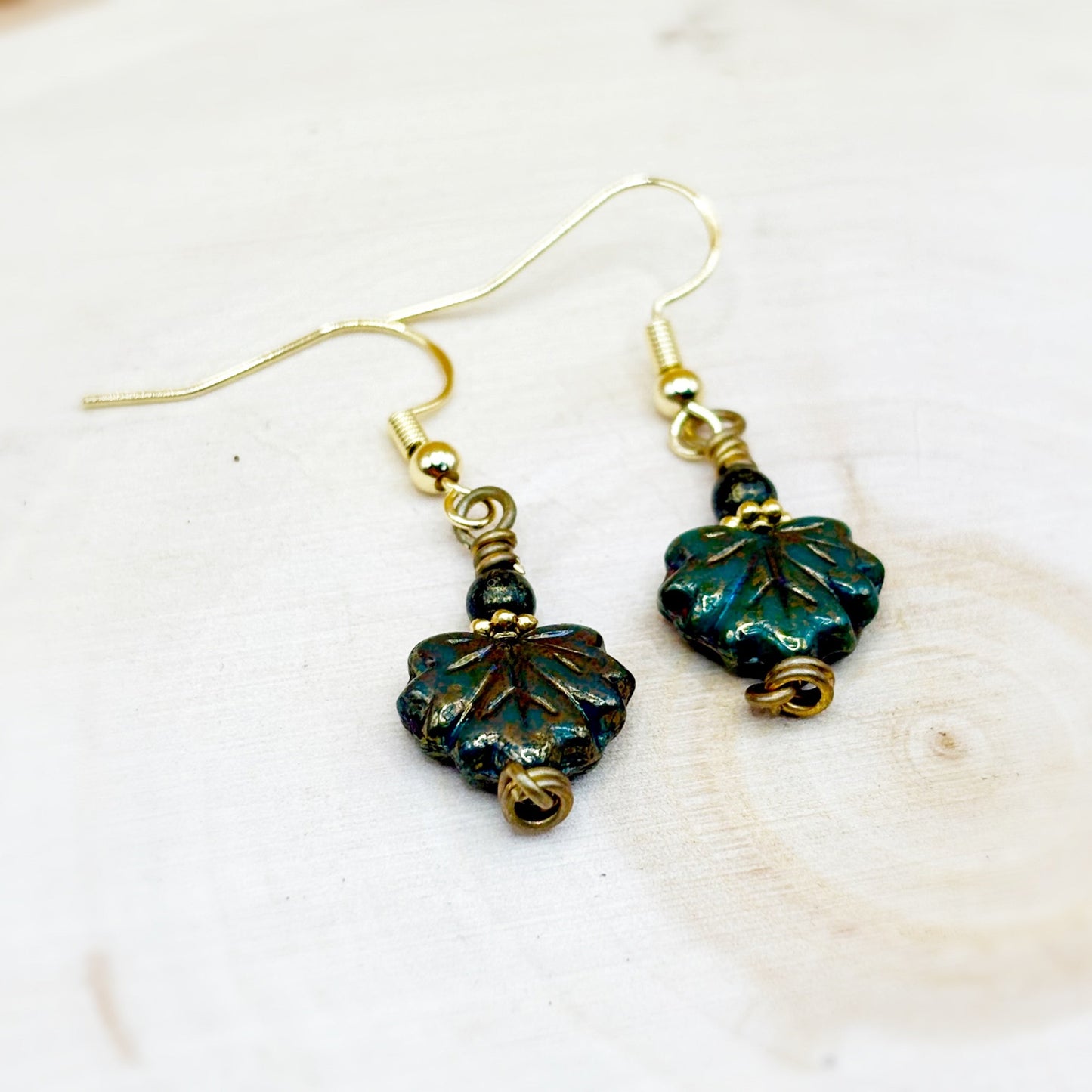 Pair of leaf-shaped earrings with gold accents on a white background