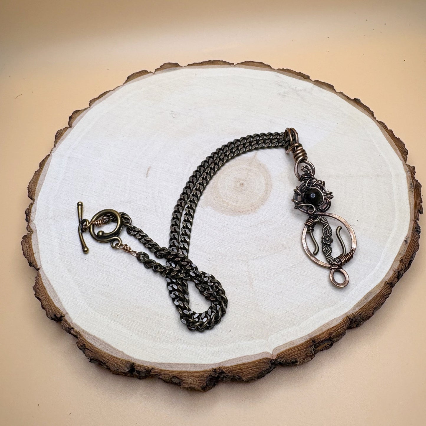 Necklace with chain and decorative clasp on a wooden stand