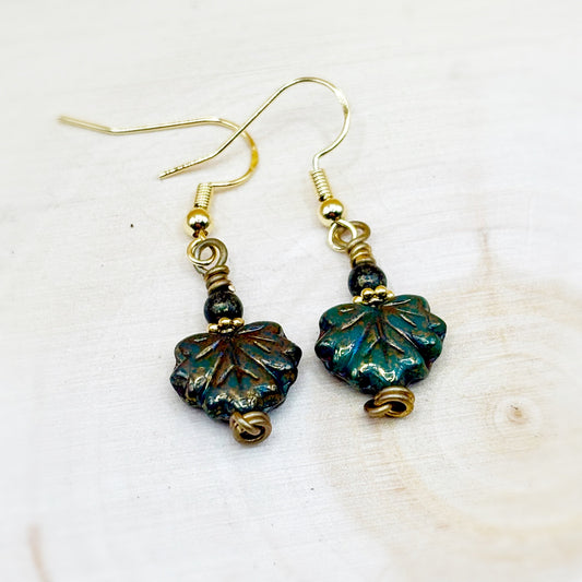 Pair of leaf-shaped earrings with gold and green accents on a white background