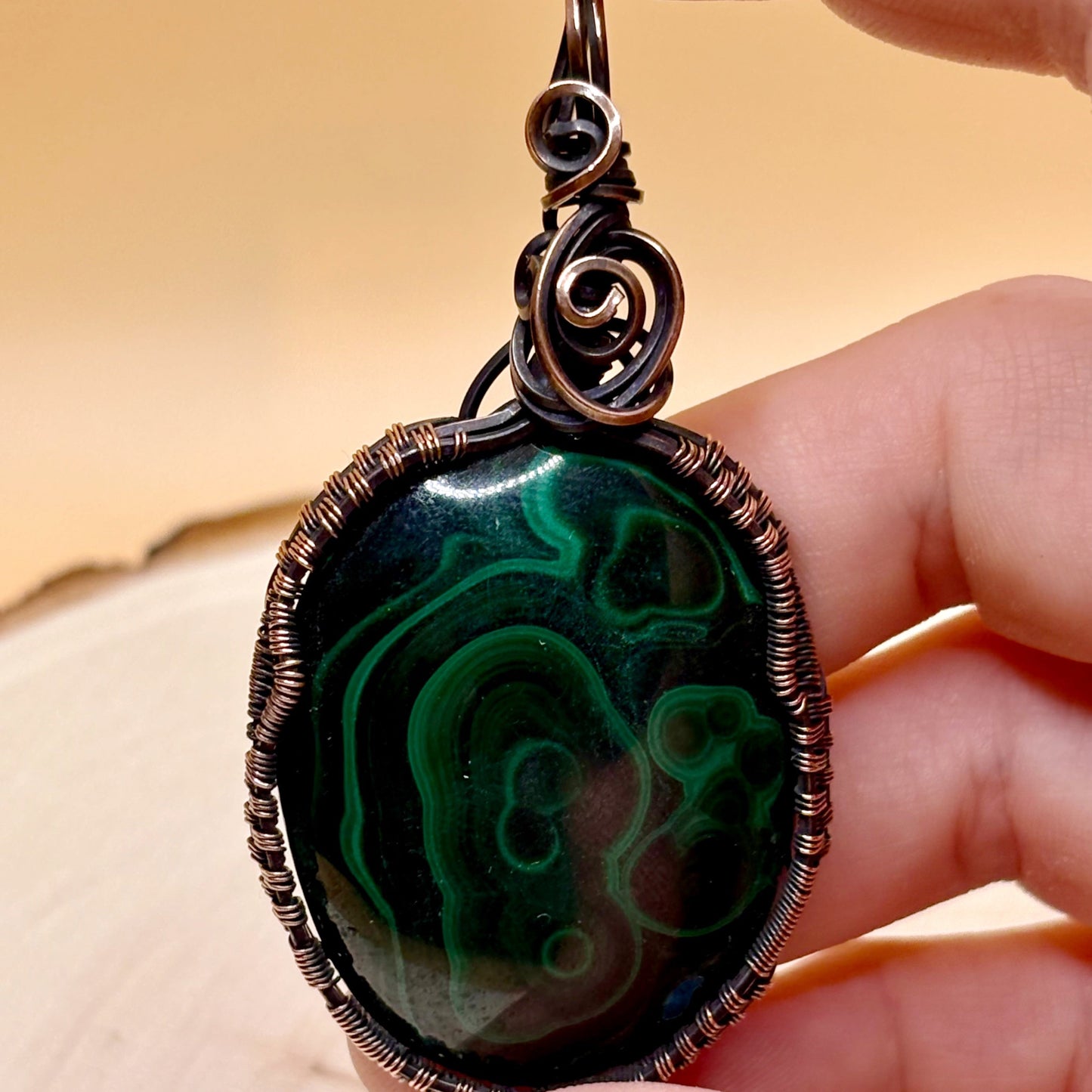 Hand holding wire wrap pendant to show size reference