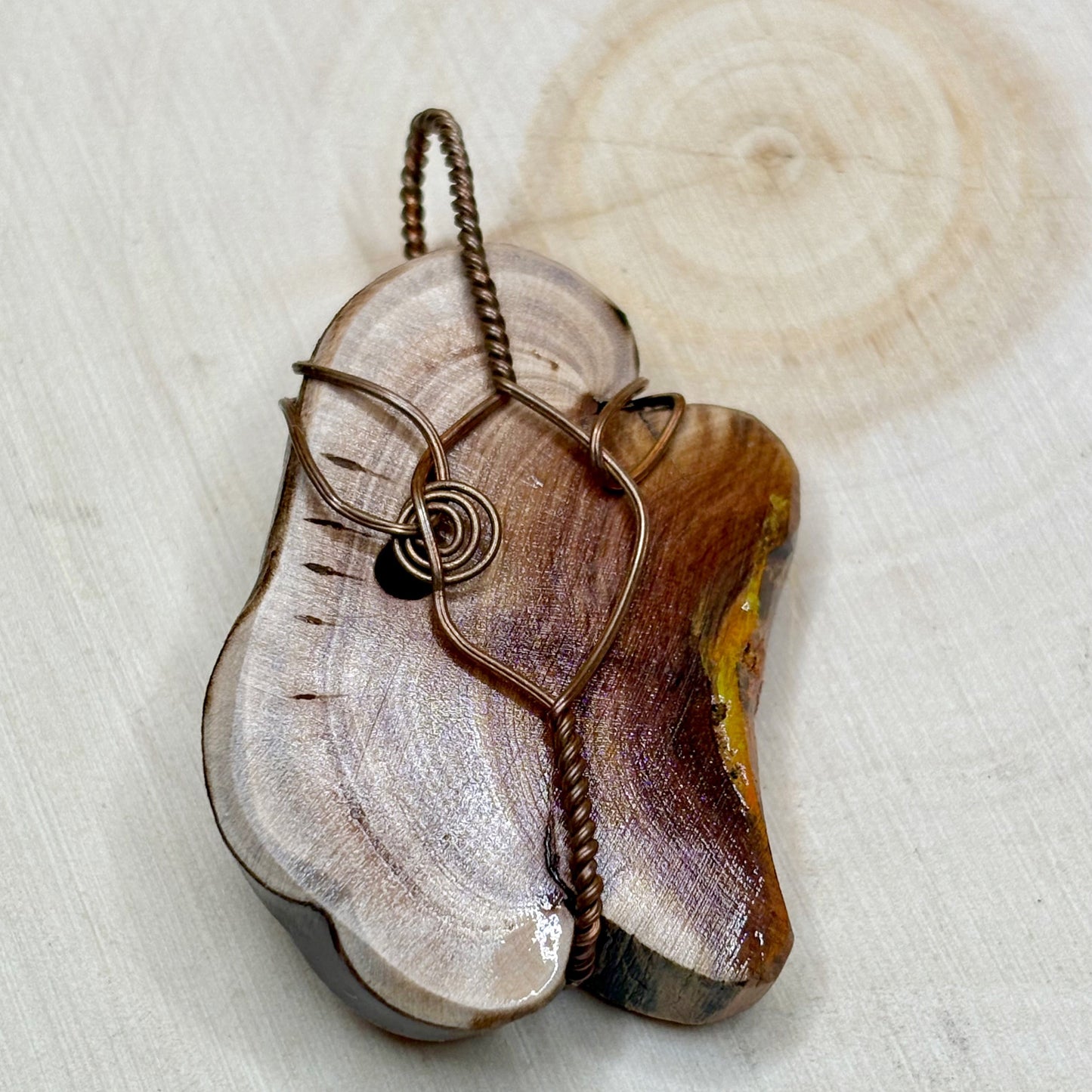 Wooden pendant with metal wire design on a wooden background