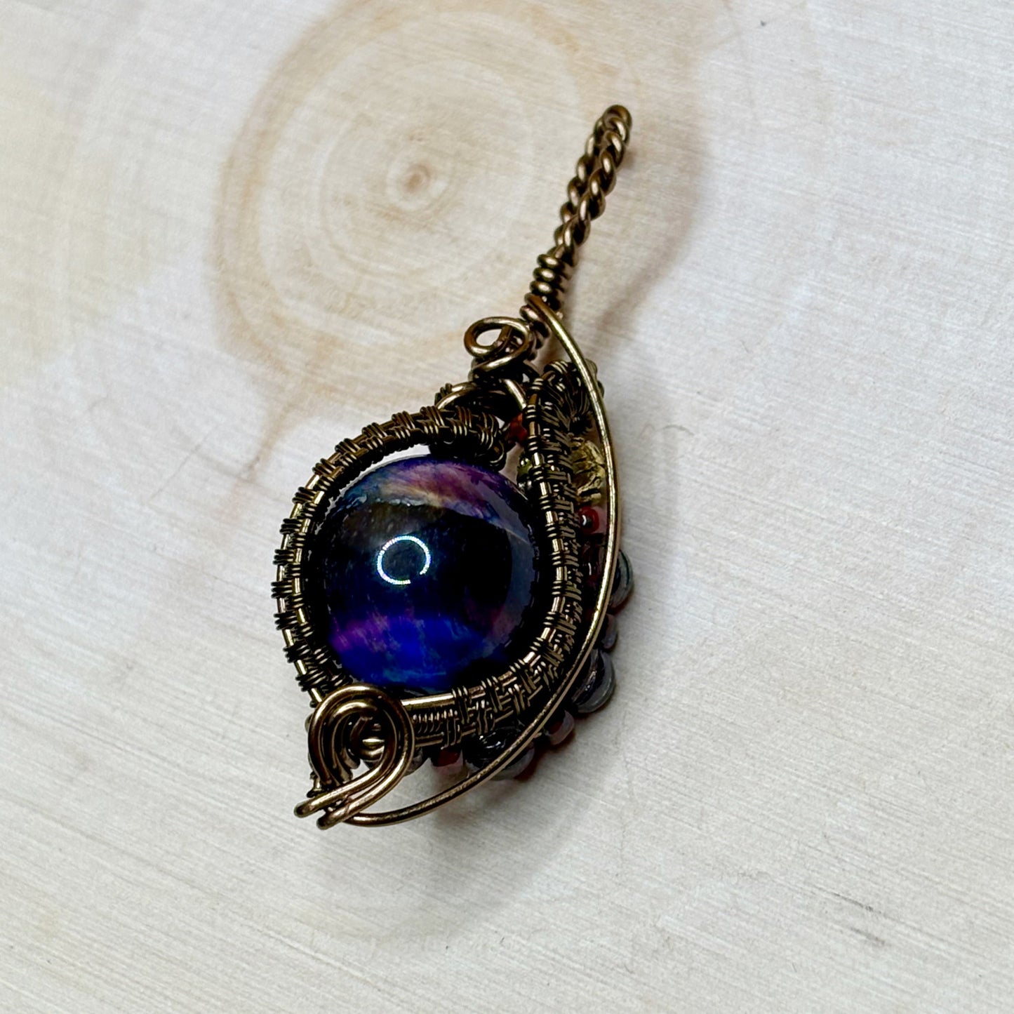 Decorative pendant with a dark blue and purple design on a wooden background