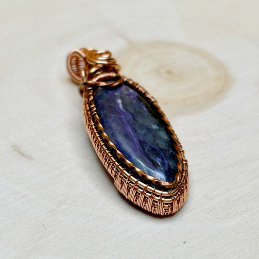 Copper-wrapped pendant with a purple stone on a white background
