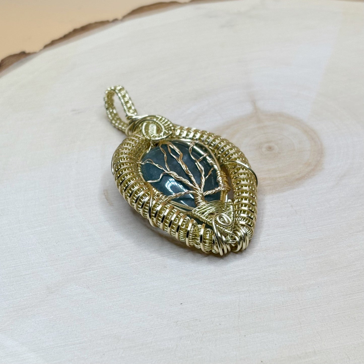 Gold pendant with tree design on a wooden background