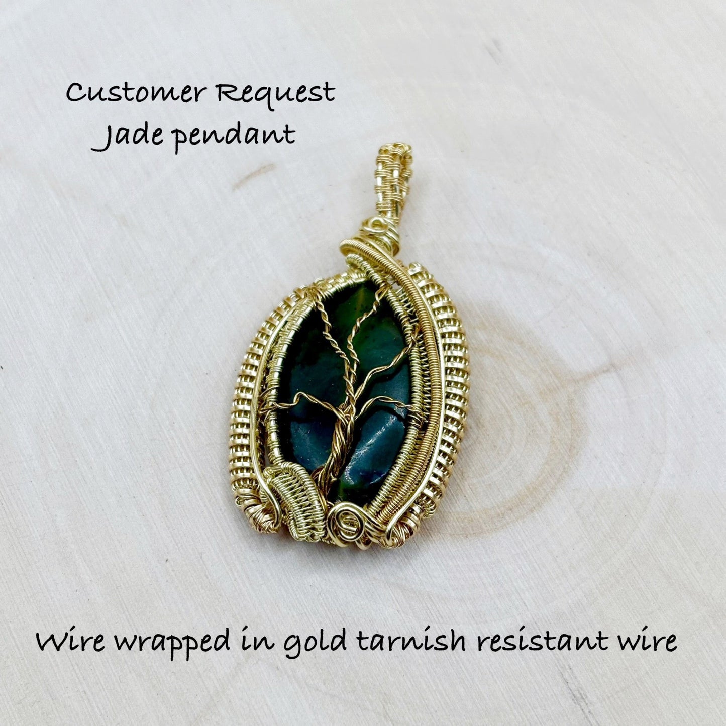 Jade pendant wire wrapped in gold tarnish resistant wire on a light background