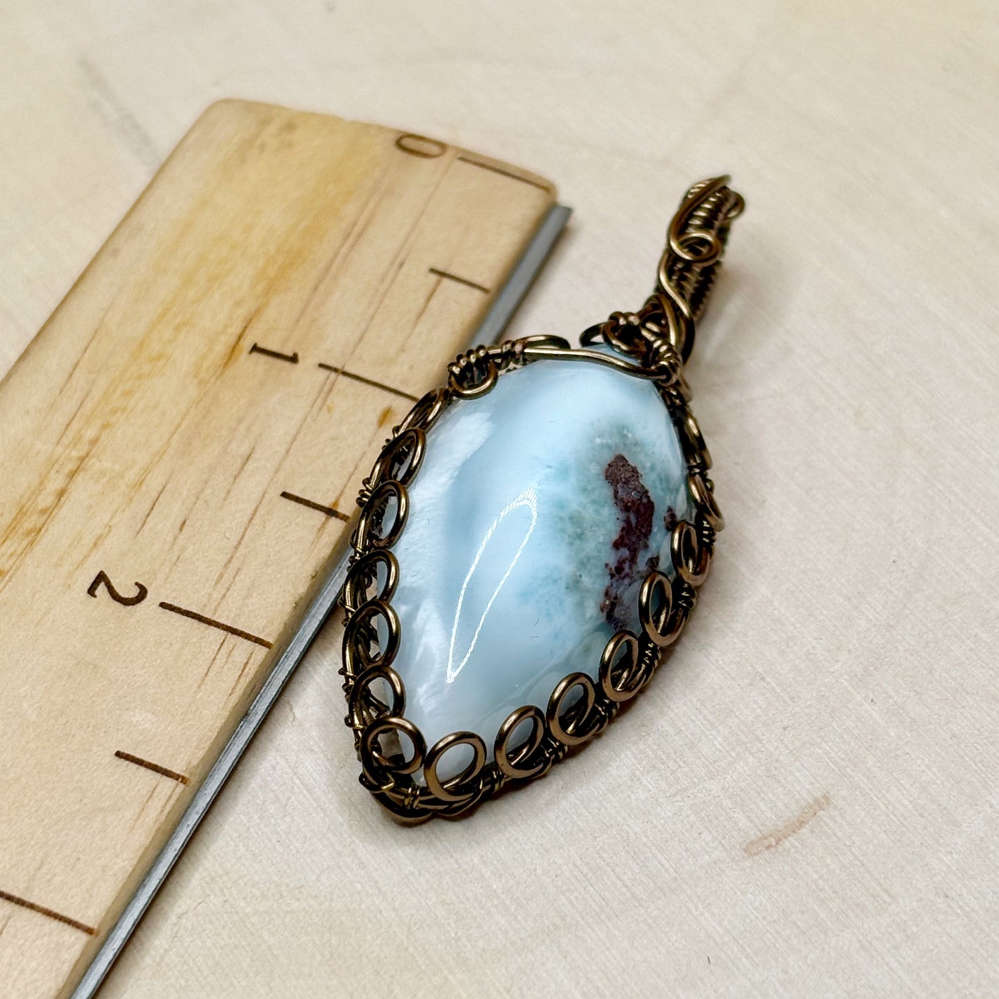 Pendant with a blue stone and antiqued bronze wire wrap on a wooden surface