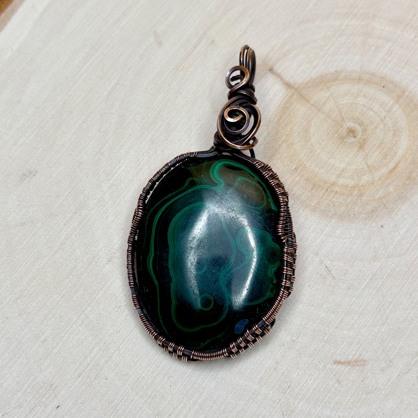 Green and blue stone wire wrapped in copper sitting on light background
