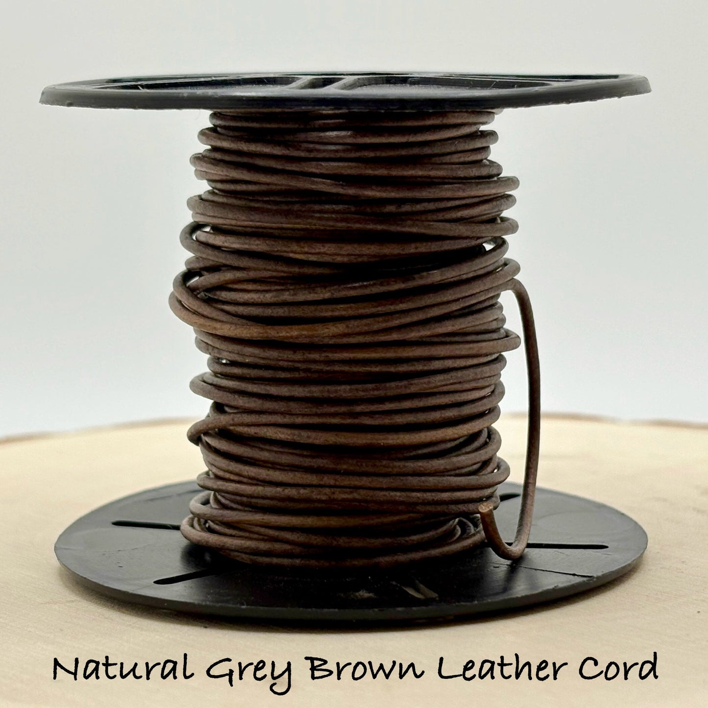 Spool of natural grey brown leather cord on a white background