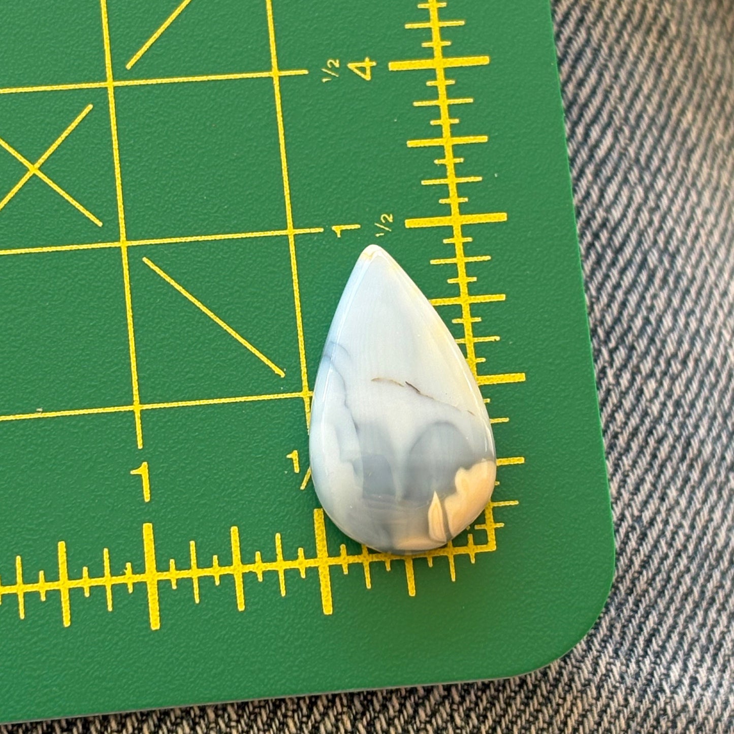 Teardrop-shaped stone on a green cutting mat with yellow measurements