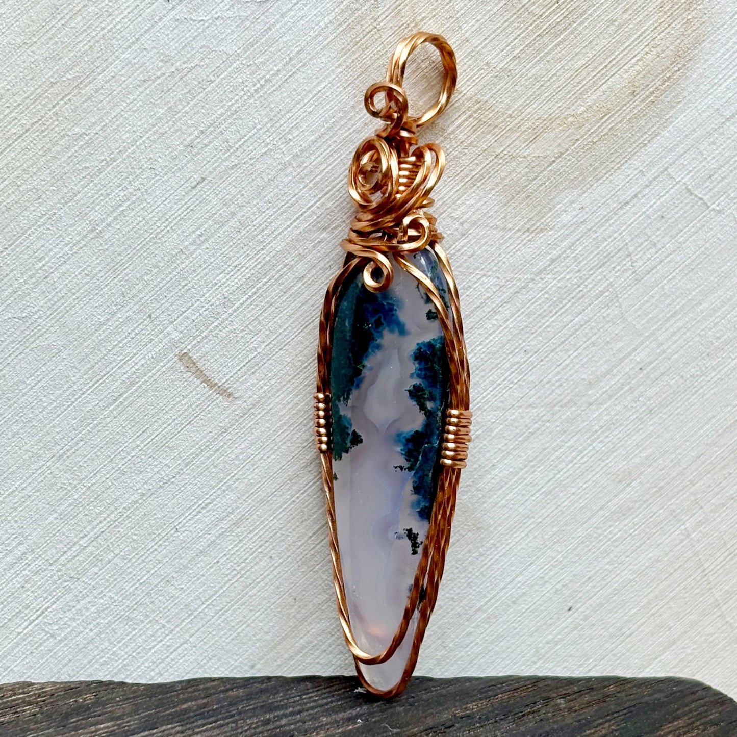 Decorative pendant with a purple and white stone on a textured surface