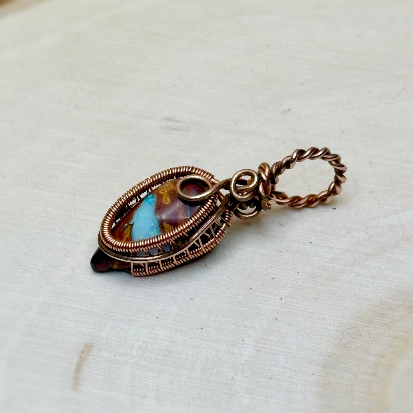 Jewelry pendant with copper wire wrapping on a white background