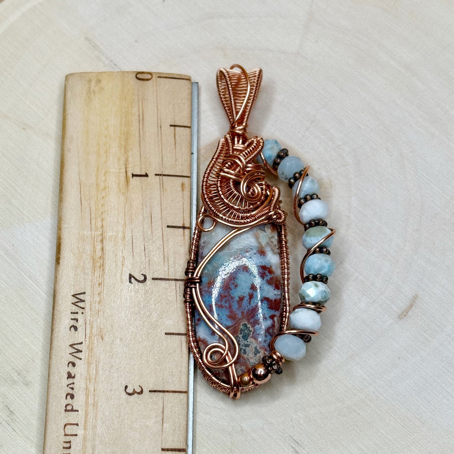 Decorative pendant with blue beads on a wooden ruler