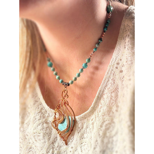 Necklace with turquoise beads and a decorative pendant worn by a person in a white lace top.