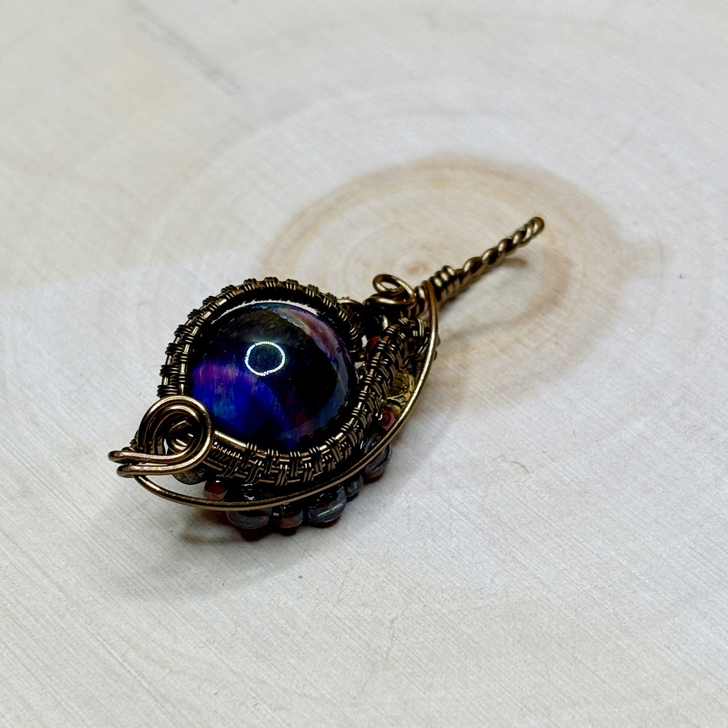 Jewelry pendant with blue gemstone on a white wooden background