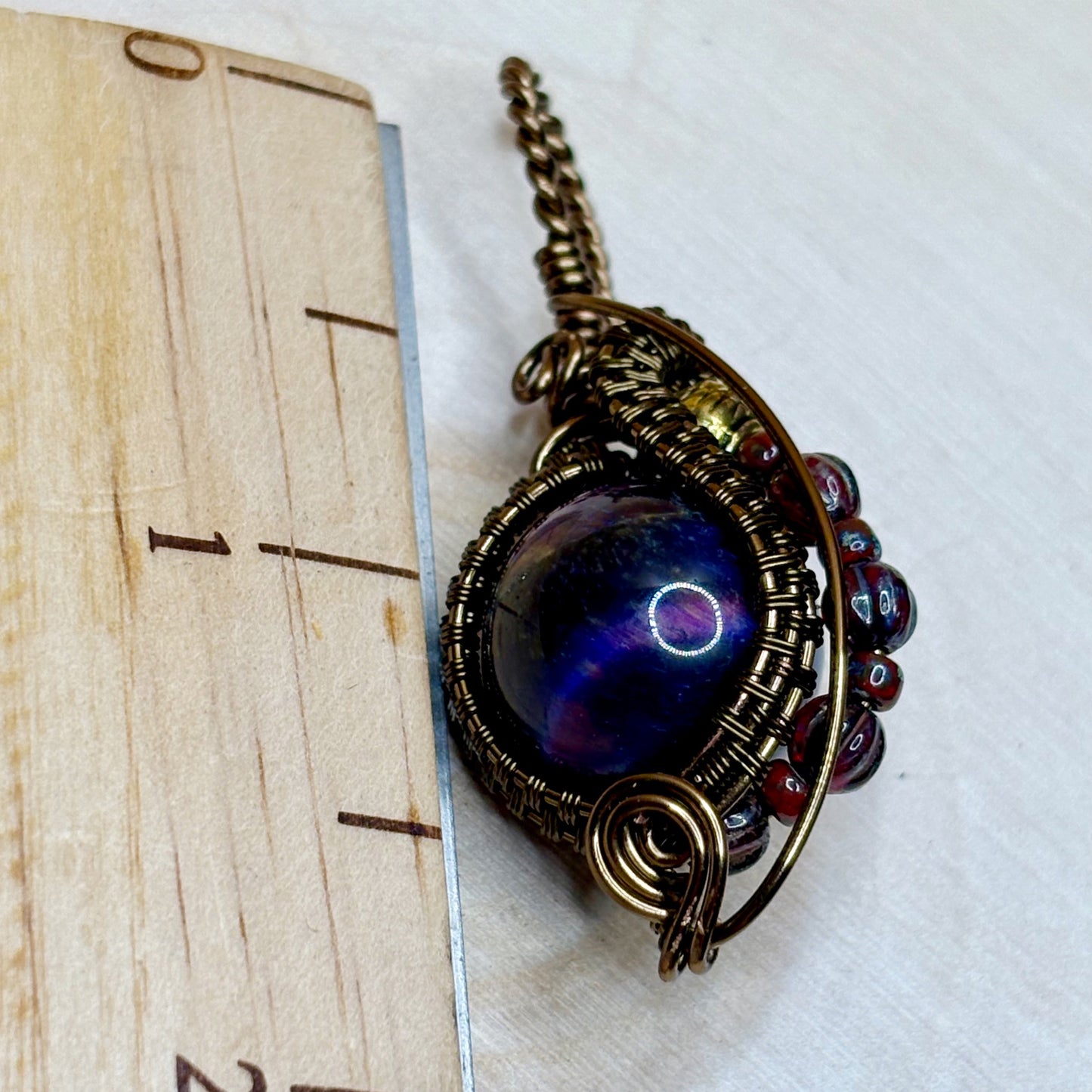 Ornate pendant with a blue gemstone on a white background