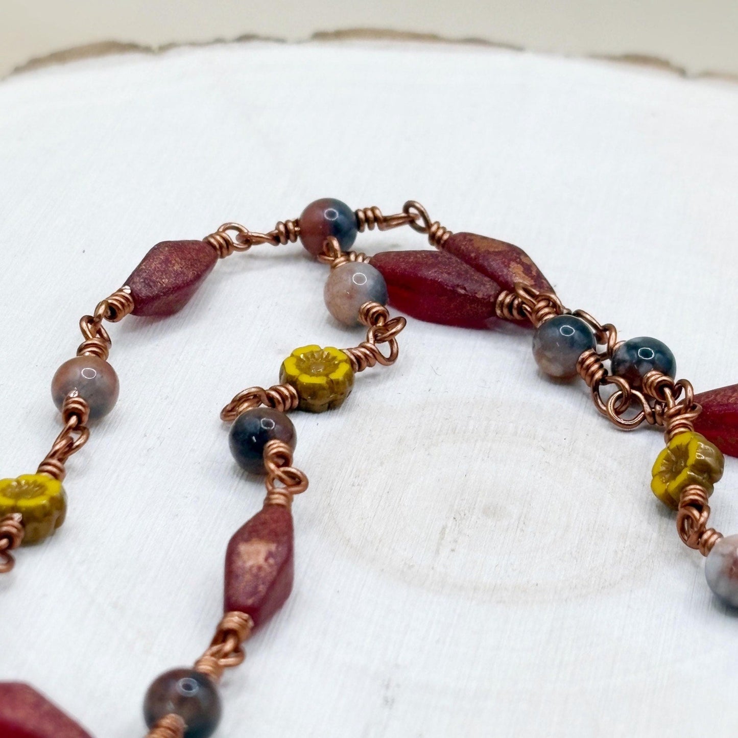 Necklace with multicolored beads on a white wood background