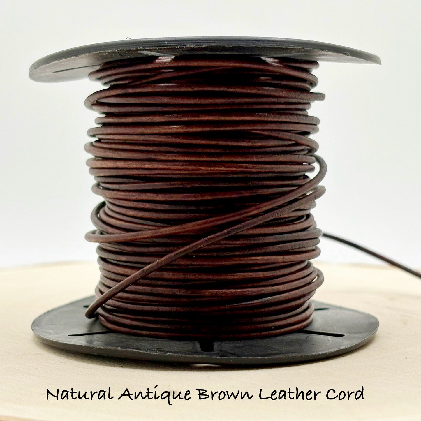Spool of natural antique brown leather cord on a white background