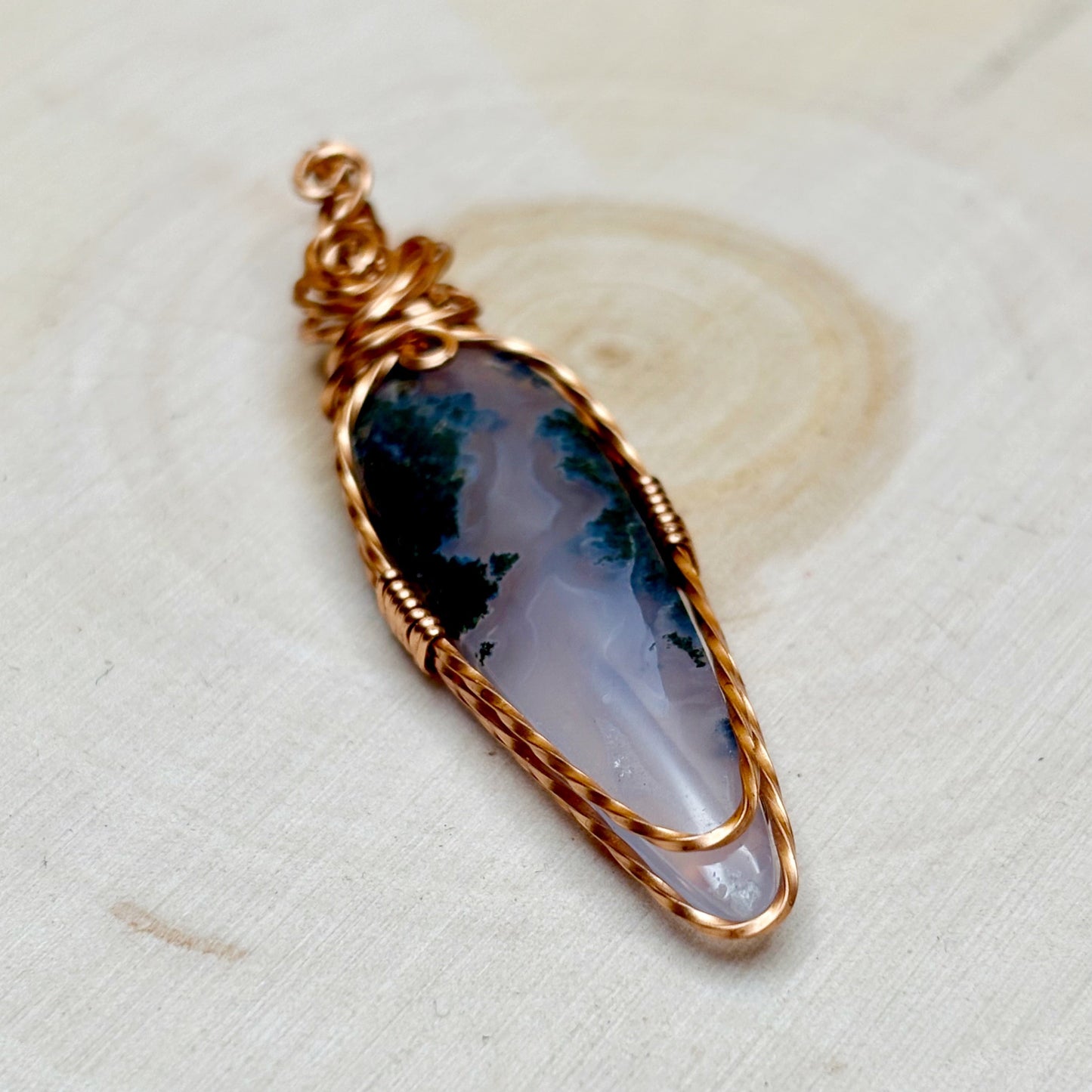 Handmade wire wrap pendant purple and green stone on wooden background