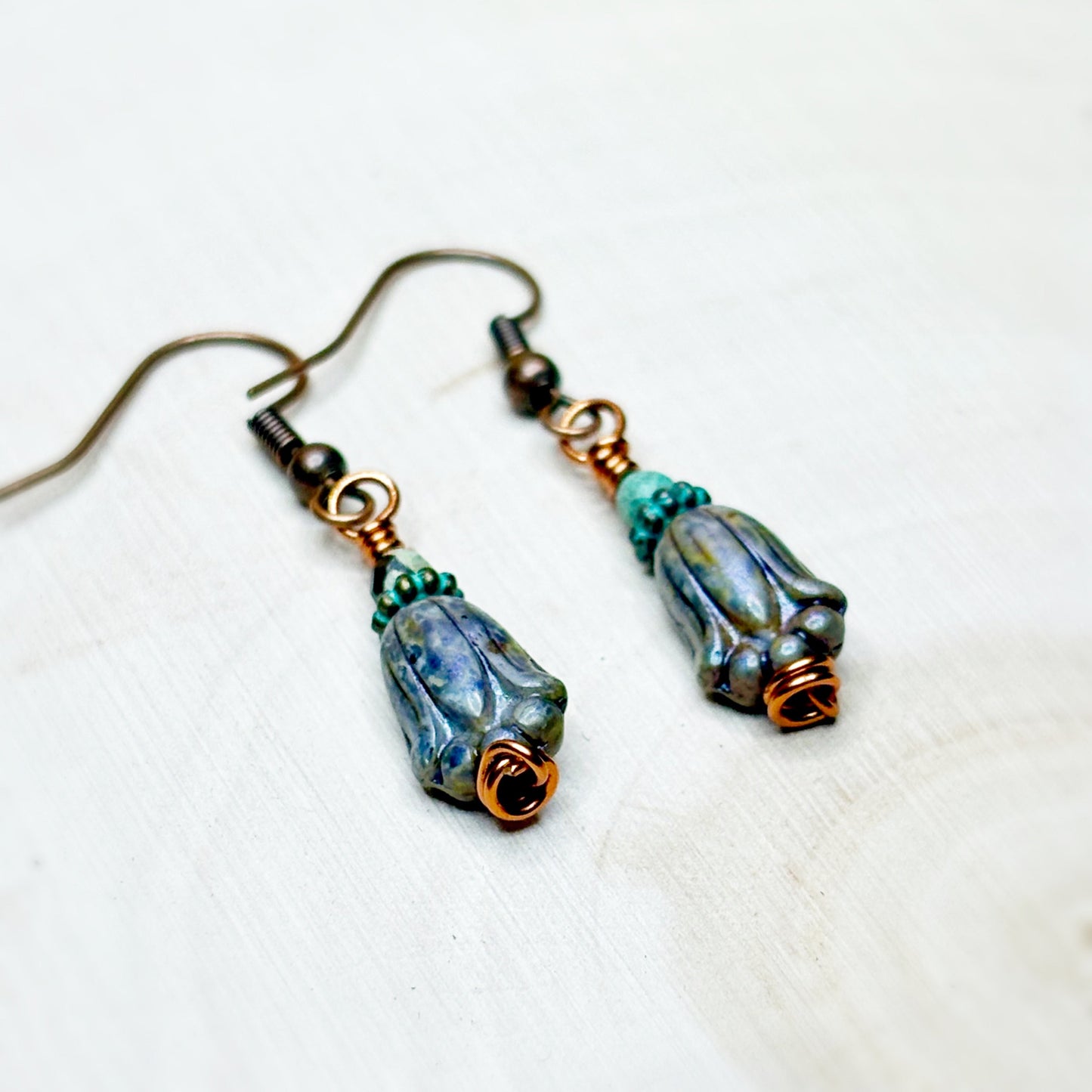 Pair of earrings with blue and green glass beads on a white background