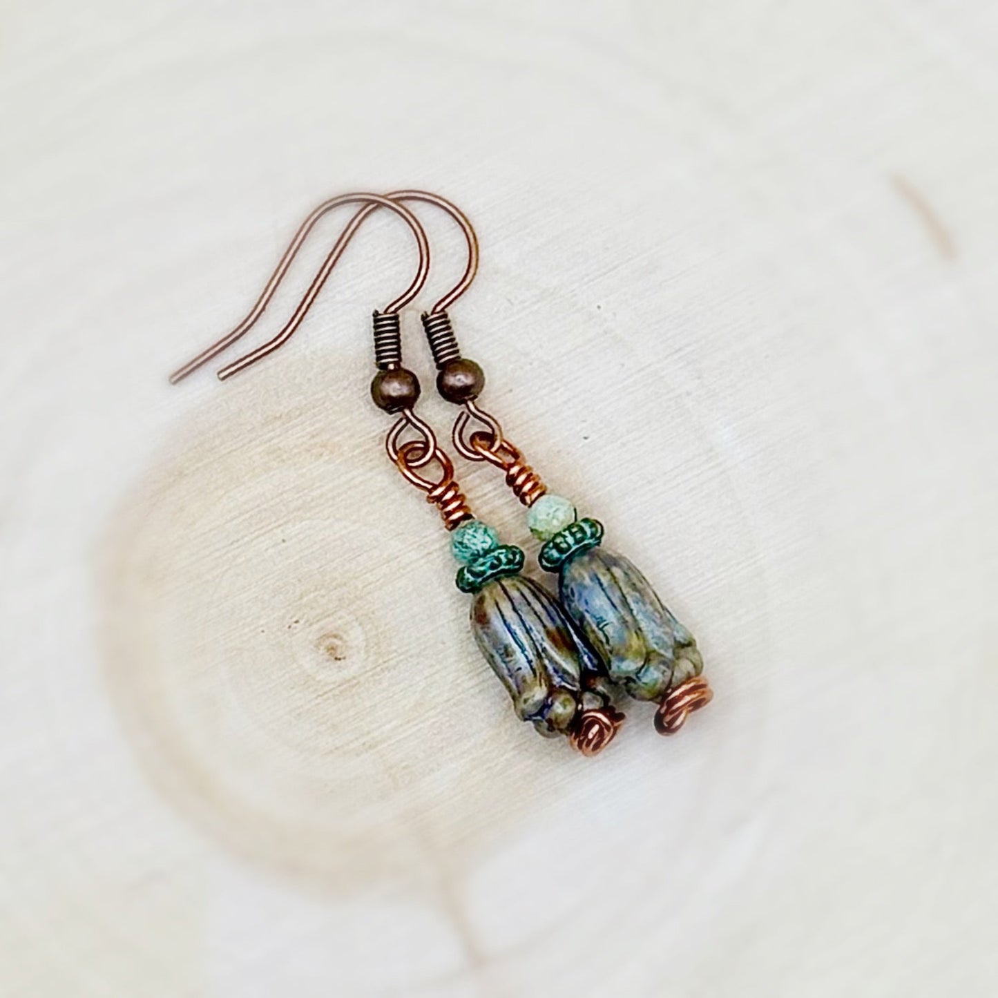 Pair of earrings with glass beads and copper wire on a light background