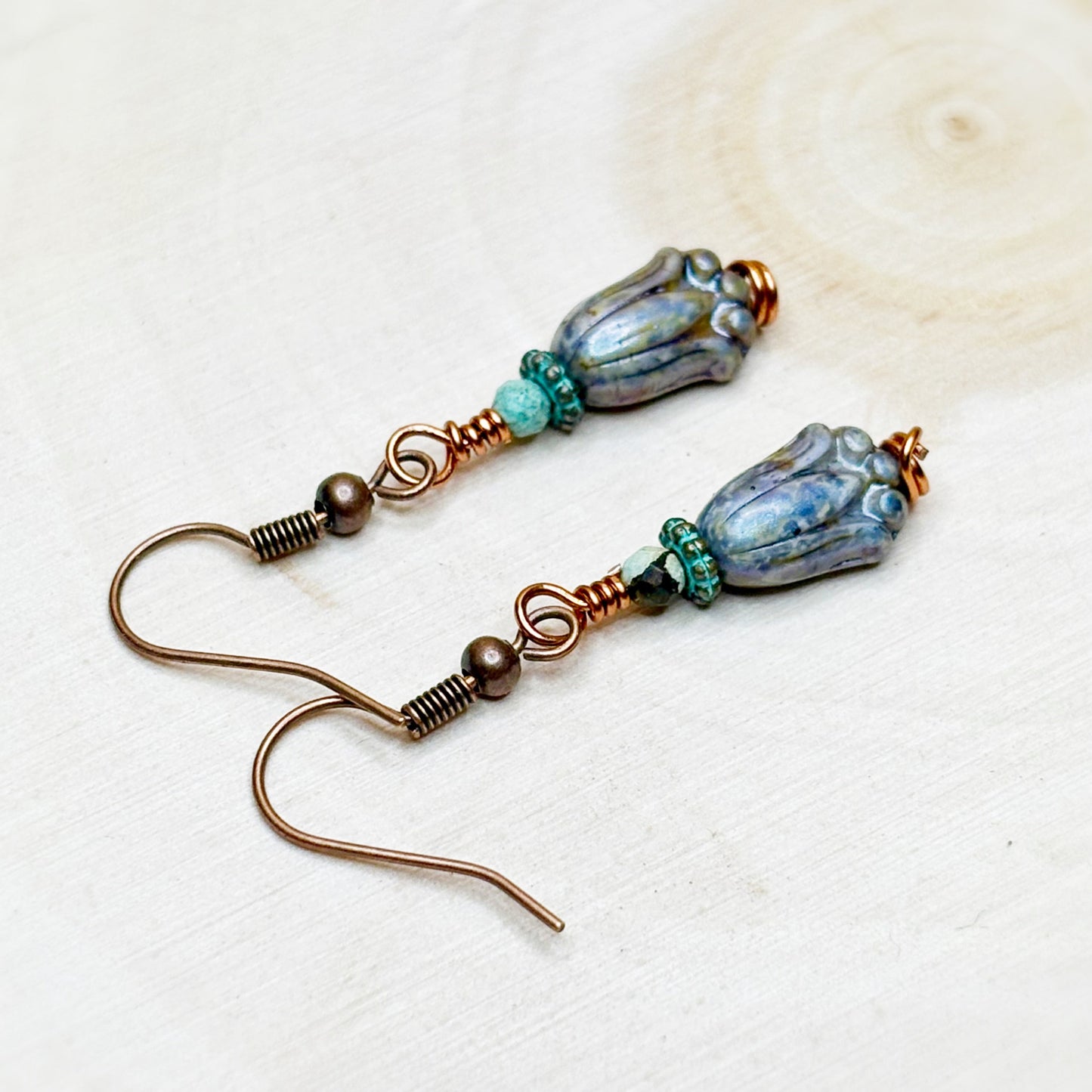 Pair of earrings with blue and brown beads on a light background