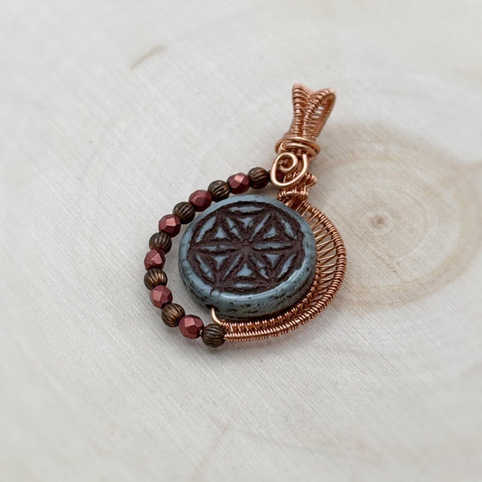 Copper and glass pendant on a light wooden surface