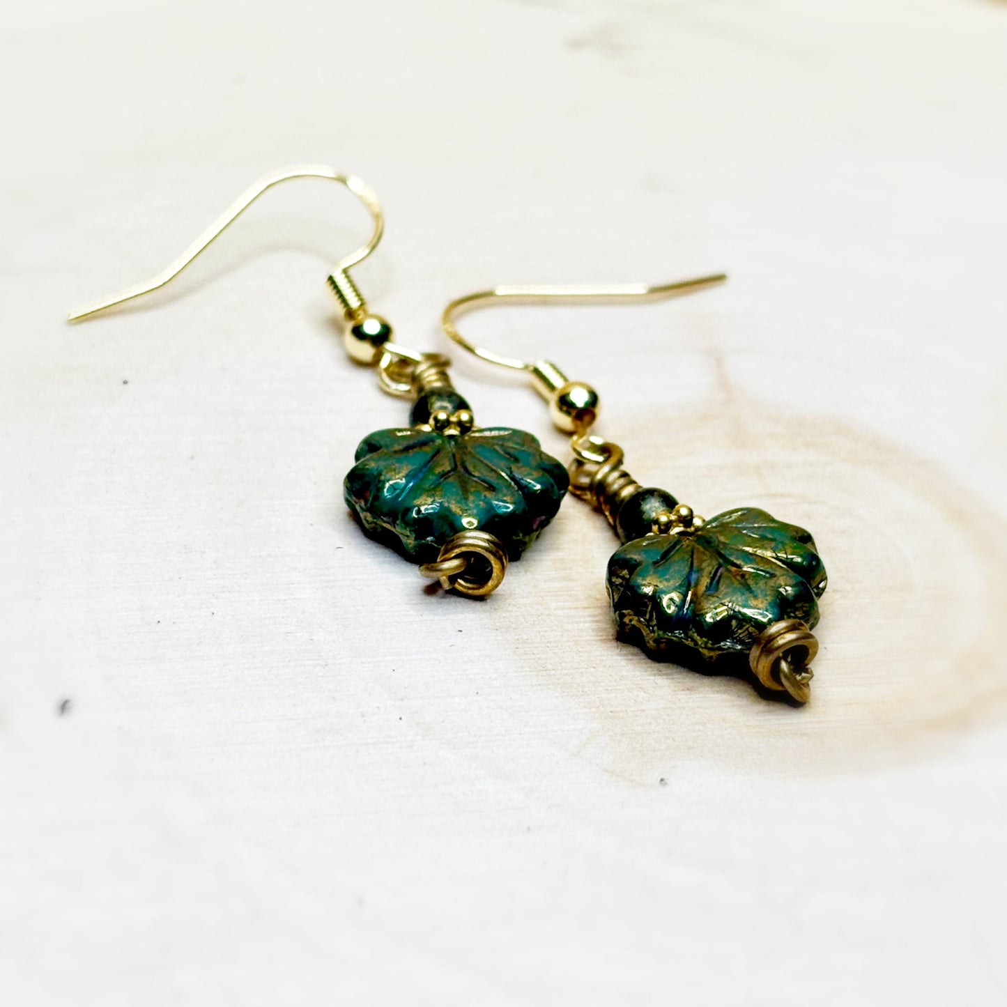 Pair of green leaf-shaped earrings on a white background