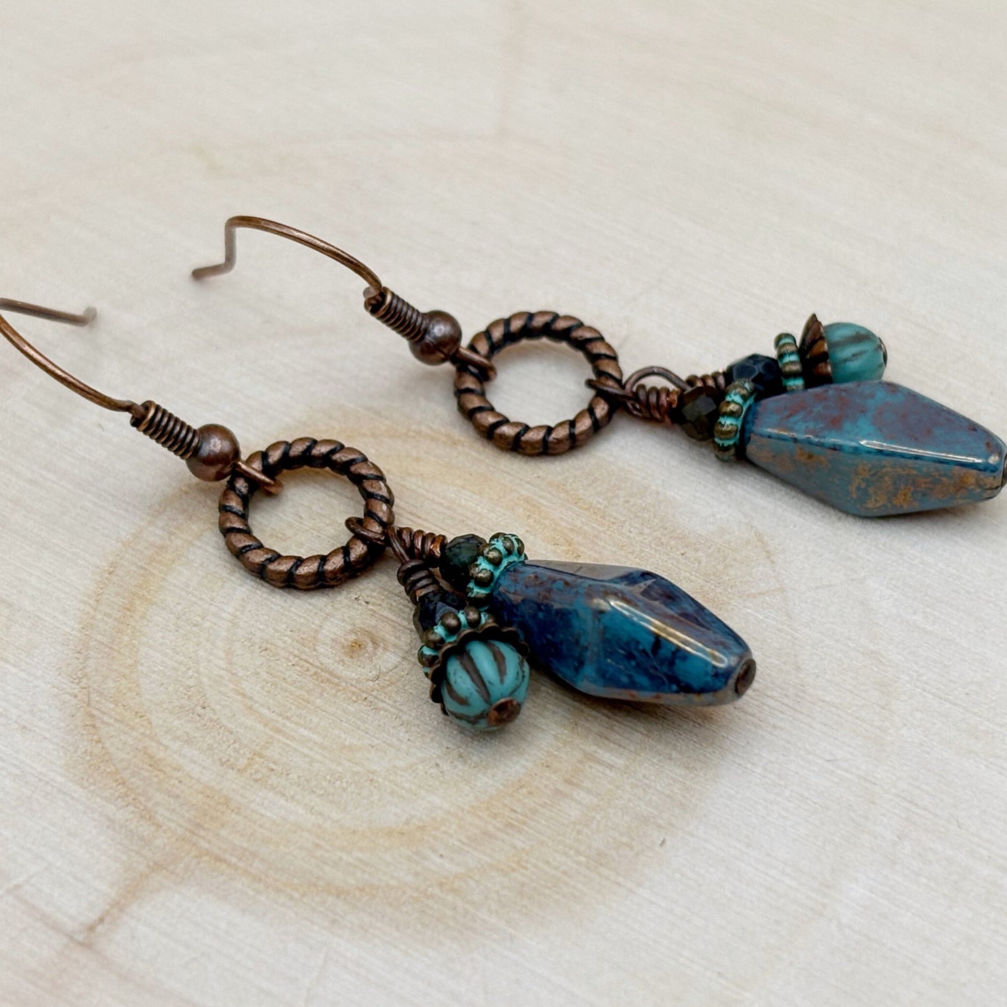 Pair of earrings with blue and brown beads on a wooden surface