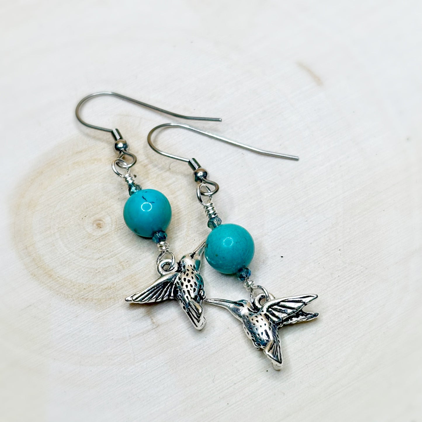 Silver hummingbird earrings with turquoise beads on a light background