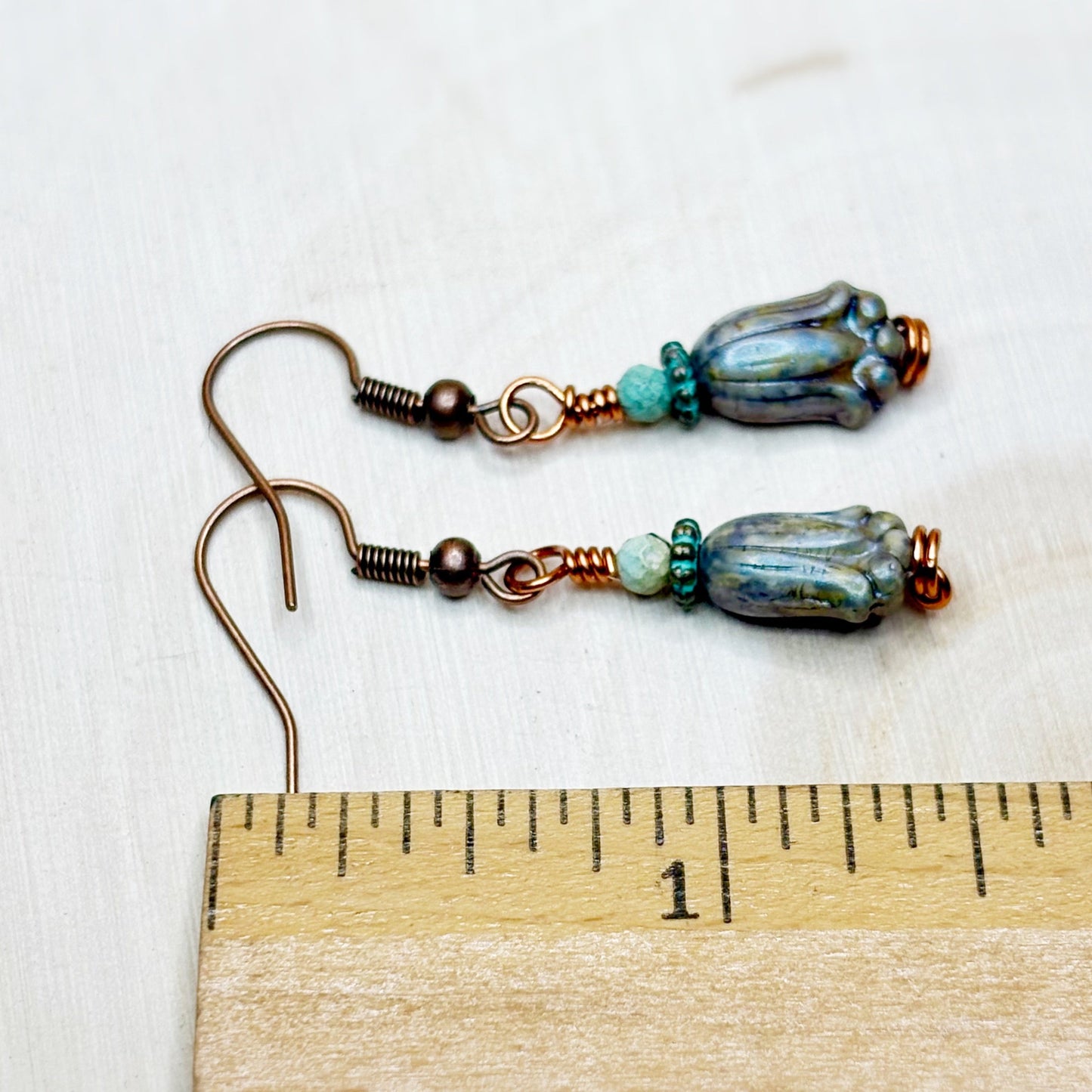 Pair of earrings with blue and green beads on a wooden ruler for scale.