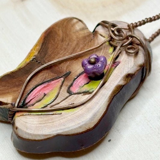 Wooden pendant with floral design and purple flower on a white background