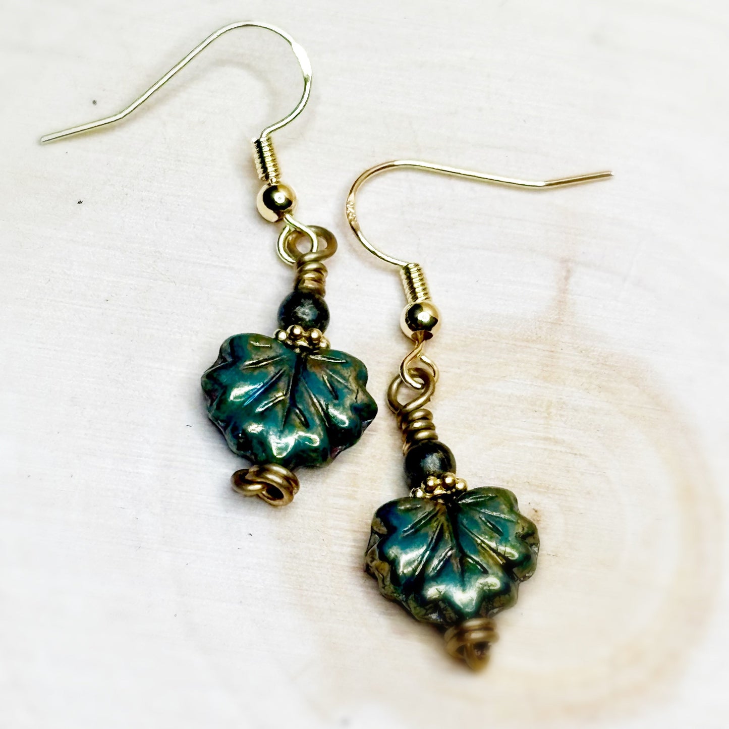 Pair of earrings with green leaf-shaped beads on a white background