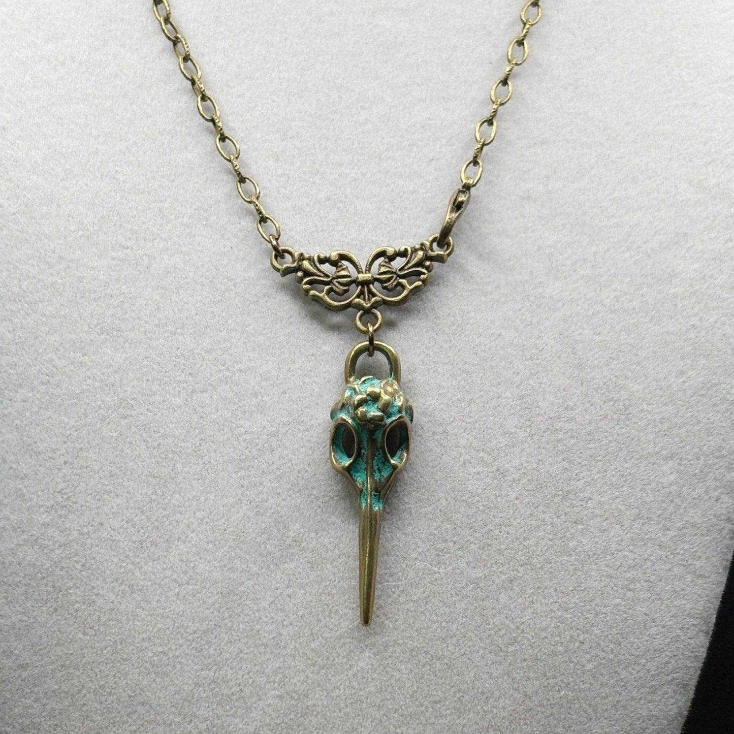 Necklace with a bird skull pendant on a light gray background