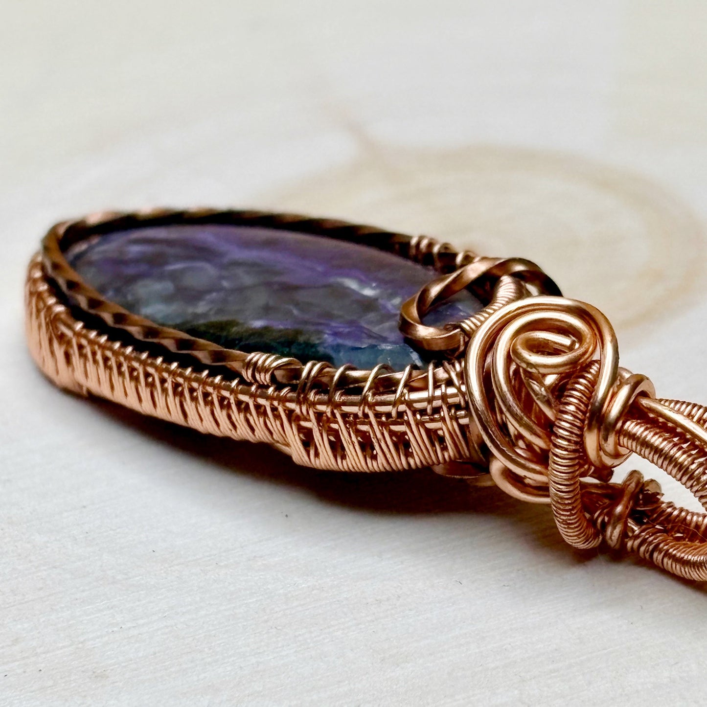 Copper-wrapped pendant with a colorful stone on a white background