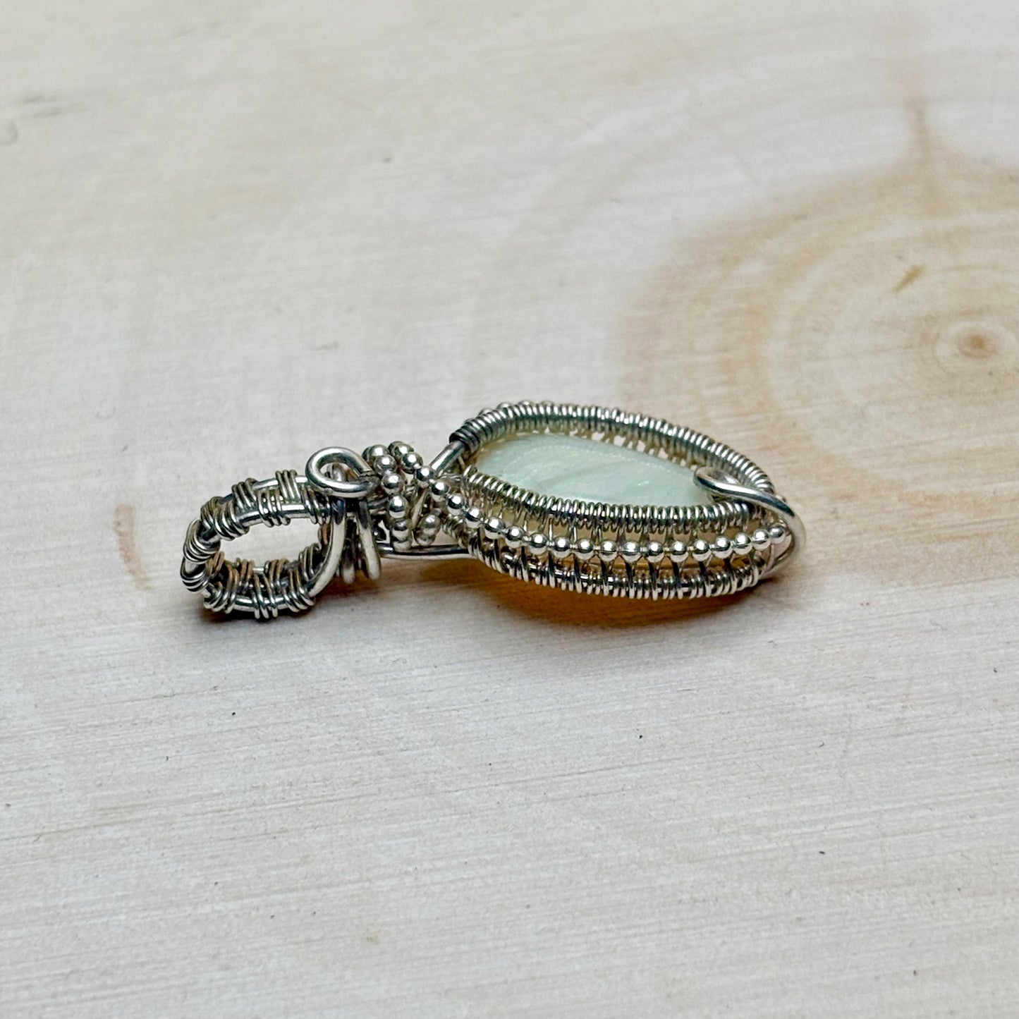 Silver pendant with a central gemstone on a light wooden surface