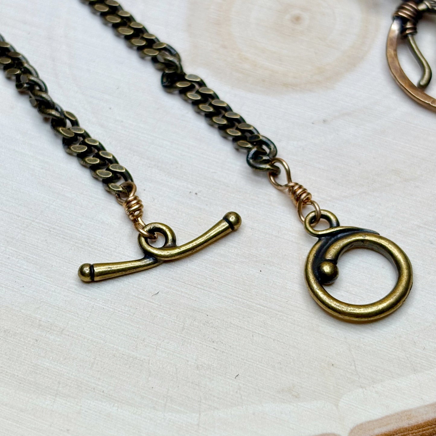 Brass chain necklace with clasp and pendant on a light background