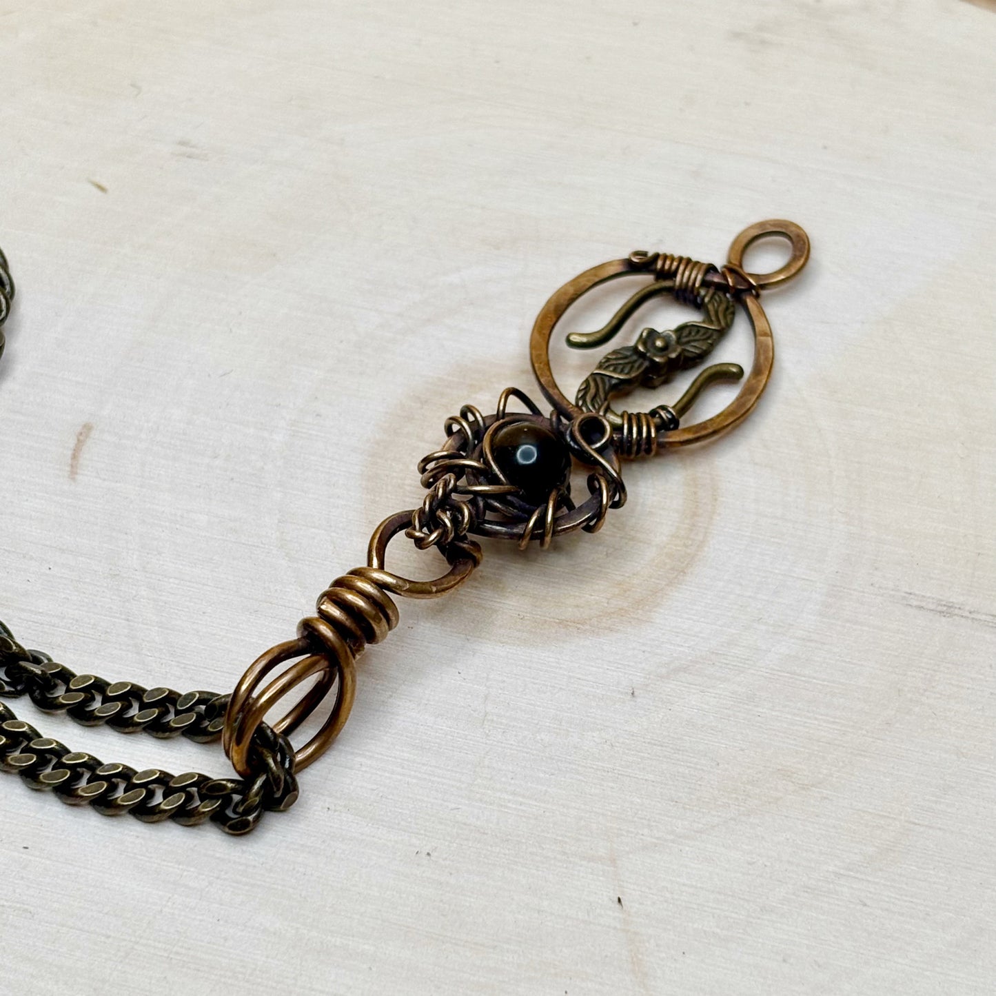 Bronze chain necklace with intricate design on a white background